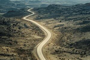 Winding dirt road through arid landscape under a hazy sky photo