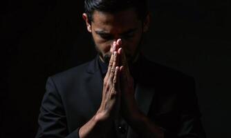 Praying hands dark background chiaroscuro lighting dramatic shadows photo