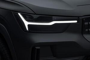 A close-up of a vehicles headlight highlights its sleek design and striking light graphic in low light, showcasing innovation in automotive engineering. photo