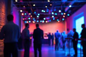 Attendees gather at a contemporary venue featuring vibrant lighting for a networking event. Individuals converse and connect, creating a lively atmosphere in the dimly lit space. photo