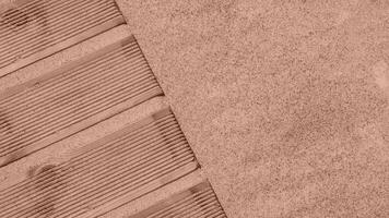 Top view of a wooden pier on the coast with sand. Abstract background from summer travel with copy space. Mocha Mousse, Color of the Year 2025. photo