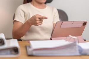 young smart woman having conference call via Tablet pad. female businesswoman Online Meeting with documents folder stack at home or office late night. Teleconference and Technology concept photo