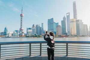 woman traveler visiting in Shanghai, China. Female Tourist with backpack sightseeing Shanghai view of Lujiazui in The Bund of Shanghai. landmark and popular for tourism attractions. Vacation concept photo