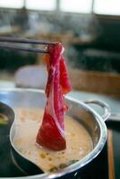 Man put to boiled soup in pot shabu by chopsticks with steam. photo