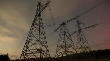 Time lapse of moving stars and clouds in the night sky. Beautiful aurora lights dance across the night sky, illuminating towering power lines in a tranquil countryside setting. video