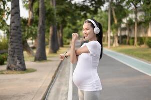 Beautiful pregnant woman stretching and exercising in the park photo