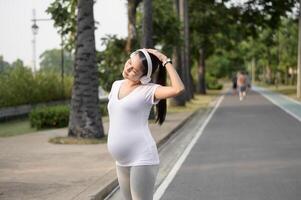 Beautiful pregnant woman stretching and exercising in the park photo
