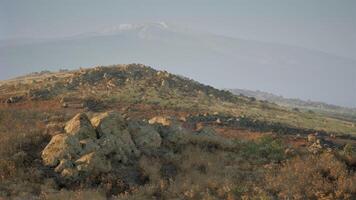 Vast landscape with rocky terrain and distant snow capped mountains at dusk video