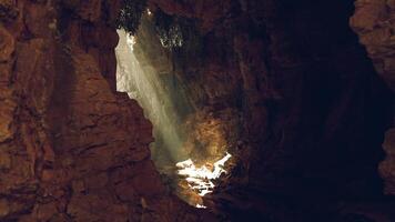 Sunlight streaming through a rugged cave along the rocky coastline at dawn video
