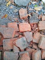 Red bricks made of clay, in broken and messy condition photo