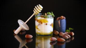 homemade yogurt with kiwi, honey and nuts in a glass, isolated on black background video