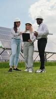 Group of three multiracial engineers at solar station checking solar panels setup. Vertical video