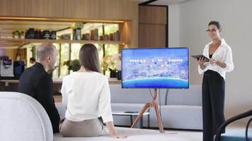 Multi-Ethnic people discussing Digital Interactive Whiteboard with real estate Data. Asian businesswoman in classic suit talking, using TV with Infographics, Statistics. AI Visualization video