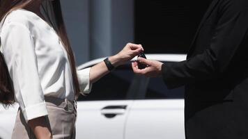 Faceless auto dealer giving key of new white car to crop male client in salon, outdoor. Handshake, Businessman completes successful car purchase transaction by give car keys after finalizing contract video