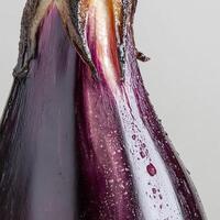Close-up of fresh eggplant with water droplets on surface, gray background. photo