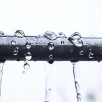 Close-up of raindrops on metal pipe with blurred grey background, highlighting nature's purity and simplicity. photo