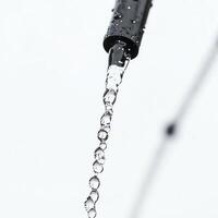Close-up of a dripping water pipe on a white background, highlighting water conservation. photo