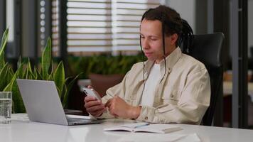 American multiracial businessman worker business man guy male work break pause holding mobile phone at desk smartphone texting message in web chat surfing corporate network reading news online using video