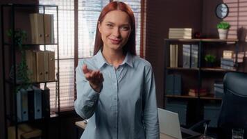 Smiling happy HR manager Caucasian business woman girl female businesswoman employer in office pointing with index finger in front hey you gesture come here invite company candidate intern invitation video