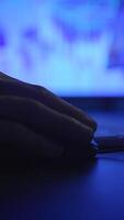 A closeup view of a hand actively using a laptop which is illuminated by blue lighting video