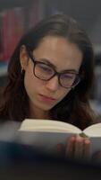 A woman is deeply engrossed in reading a book while seated in a tranquil library setting video