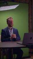 A professional man dressed in a tailored suit is working on his laptop against a green background video