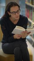 A Focused Reader Deeply Enjoying a Book While Sitting Comfortably in a Modern Library Setting video