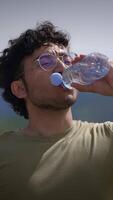 un joven hombre disfrutando un refrescante bebida de agua mientras rodeado por hermosa naturaleza video