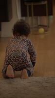 A joyful toddler is crawling around on the floor while dressed in a colorful, playful outfit video