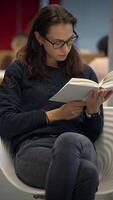 A student is engaged in reading in a modern library filled with diverse resources video