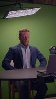 A man in a suit uses a laptop in front of a green screen, perfect for production video