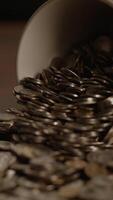 A Large Number of Overflowing Coins Piled High in a Decorative Bowl on a Wooden Surface video