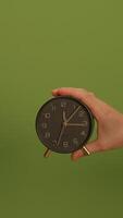 An Elegant Clock Handheld Displayed Beautifully Against a Green Background Setting video