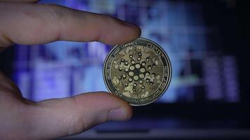 A Hand Holding Cryptocurrency Coin in Front of a Digital Background Displaying Data and Trends video