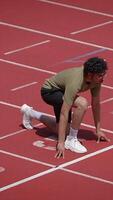 An athlete getting ready to sprint powerfully on a running track, preparing for the race video