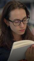 A Young Woman Engrossed in Reading a Book with Intense Focus in a Library Environment video