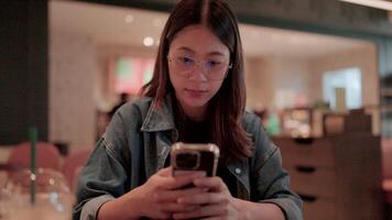 Smiling woman talking on mobile phone in a cafe while drinking coffee video