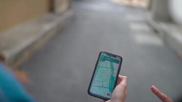 Navigating the City.A close-up shot of a person's hand holding a smartphone displaying a map app, with another person in the background wearing a mask. video