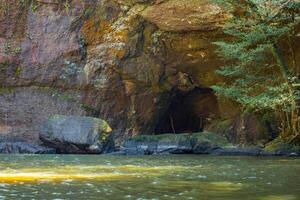 Serene river flowing through a forest with a cave. National park, Thailand. photo
