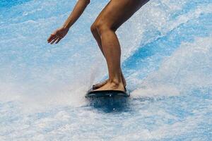 Surfer balancing on a surfboard. Water sports activity. Instructor demonstrating how to stand up on surfboard. The concept of practice and perseverance before it succeeds. Blue Background photo