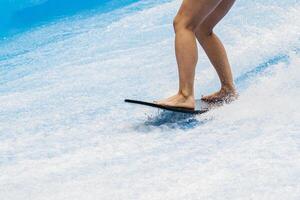 Surfer balancing on a surfboard. Water sports activity. Instructor demonstrating how to stand up on surfboard. The concept of practice and perseverance before it succeeds. Banner, copy space photo