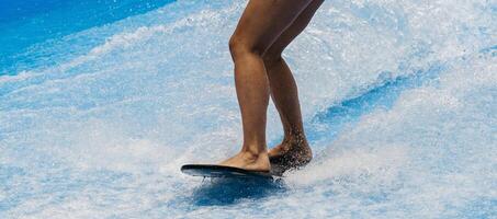 Barefoot surfer balancing on a surfboard. Water sports activity. Demonstration how to stand up on surfboard. The concept of practice and perseverance before it succeeds photo