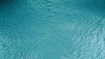 a blue water surface with waves and ripples. Rough patterned texture background. Abstract liquid water painting. Aqua color textured photo