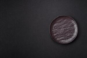 Empty black ceramic plate on a dark concrete background photo