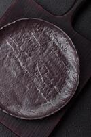 Empty black ceramic plate on a dark concrete background photo