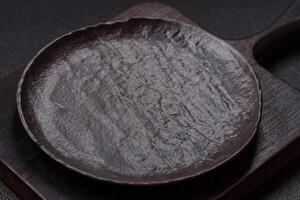 Empty black ceramic plate on a dark concrete background photo
