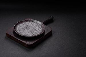 Empty black ceramic plate on a dark concrete background photo