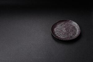 Empty black ceramic plate on a dark concrete background photo