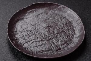 Empty black ceramic plate on a dark concrete background photo
