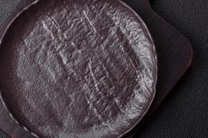 Empty black ceramic plate on a dark concrete background photo